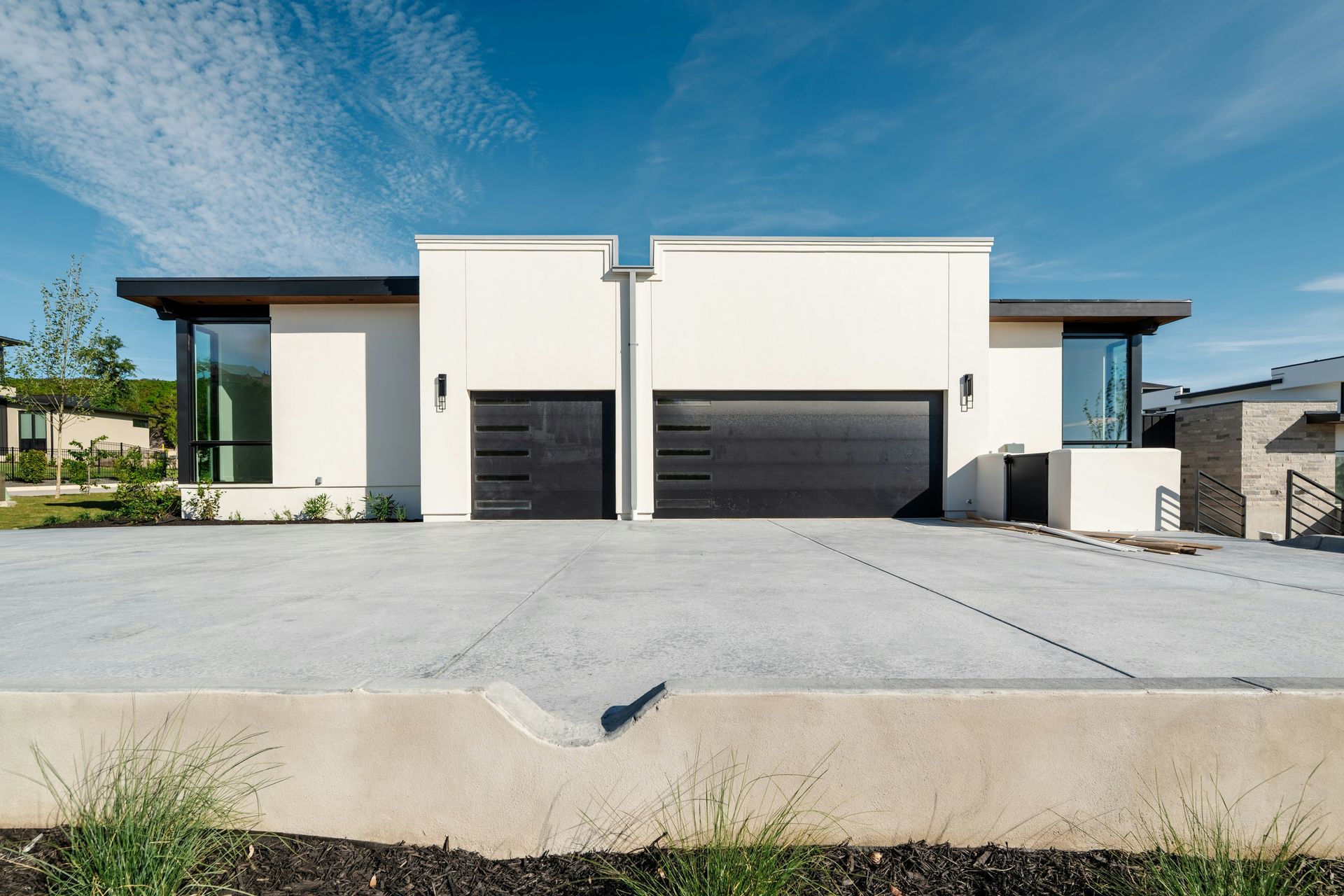Two contemporary white homes with black garage doors.