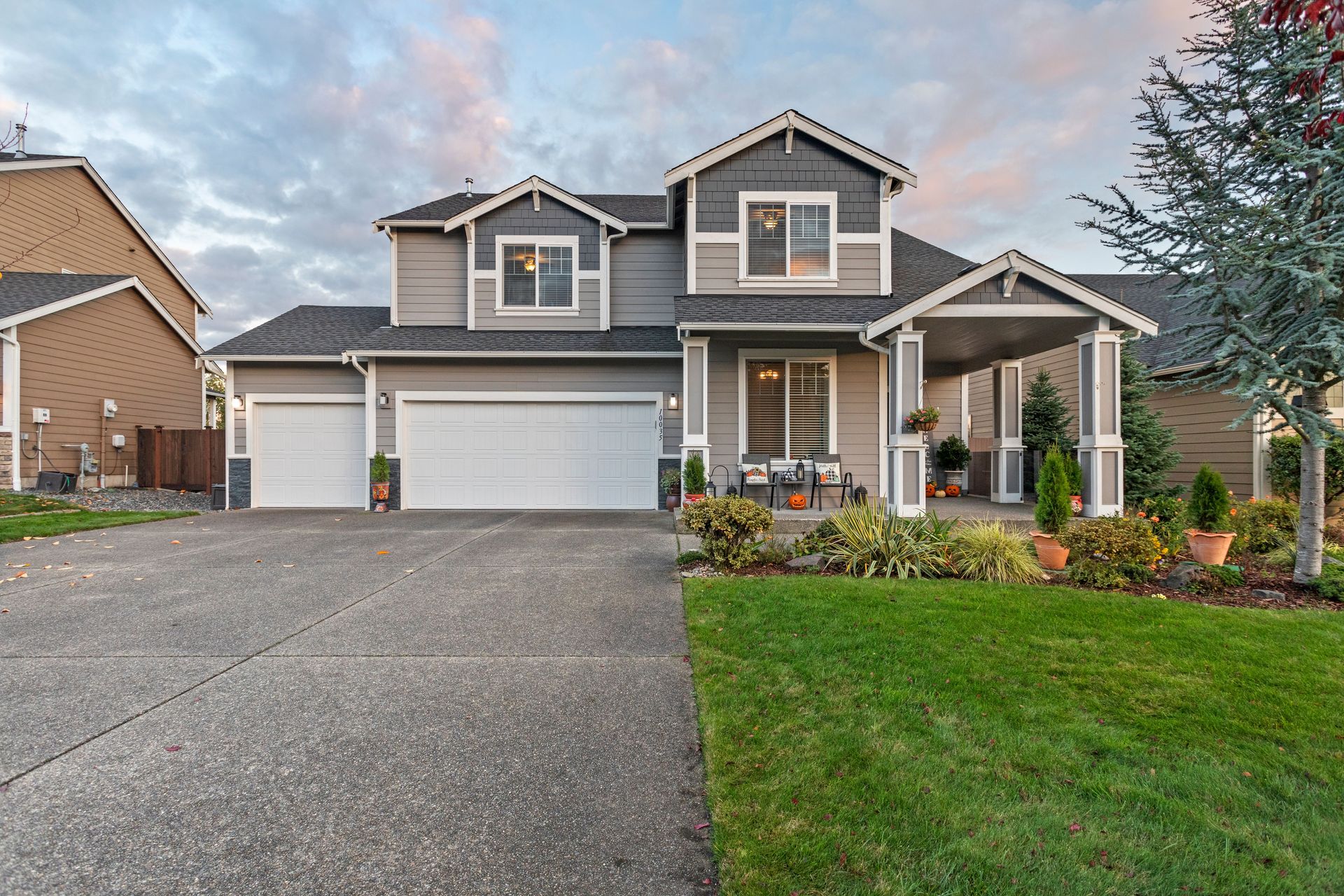 Charming two-story house with manicured lawn and garage, set in Yelm, WA, under dusk sky.